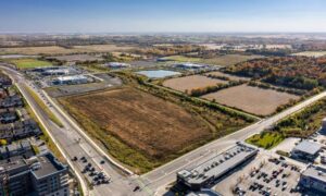 Aerial view of a commercial property with nearby buildings, roads, and open land prepared for development