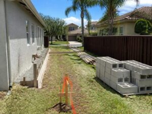 Survey stakes and foundation layout for a home addition on a narrow residential lot in Miramar, Florida.